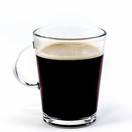 Tazza in vetro trasparente con manico, riempita di caffè con uno strato di crema chiara in superficie, su fondo bianco.