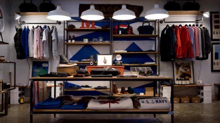 Interno di un negozio di abbigliamento con capi appesi su appendini e scaffali